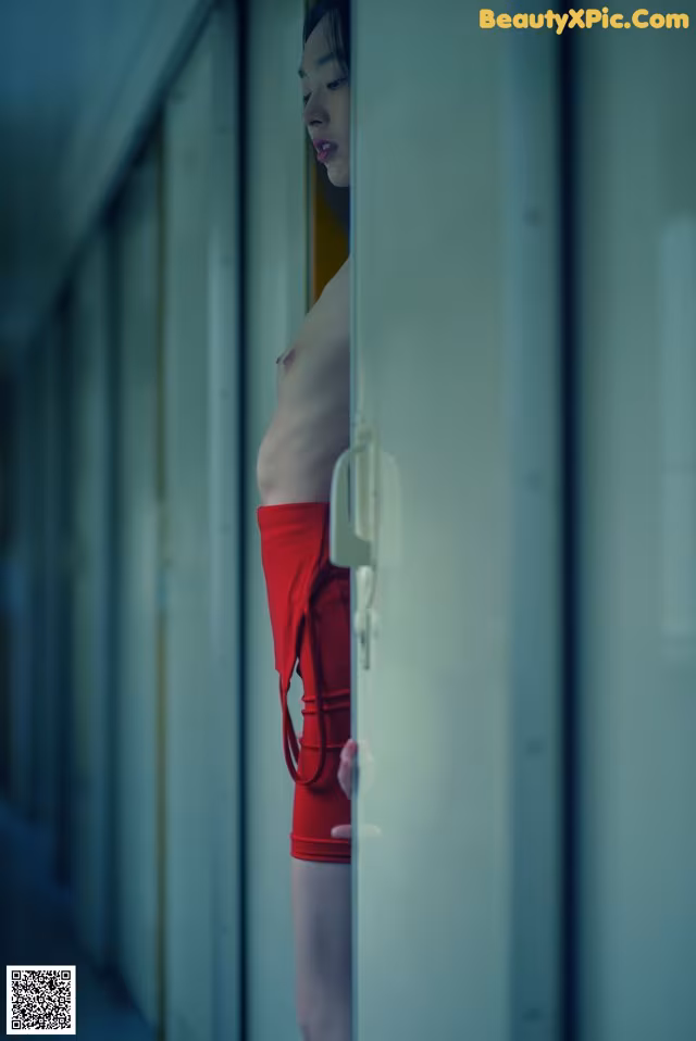 A woman in a red bathing suit standing in a hallway.