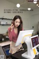 A woman standing in front of a cash register talking on a cell phone.