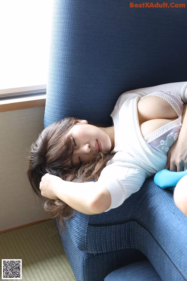 A woman laying on a blue chair with her eyes closed.