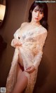 A woman in a white lace robe posing for a picture.