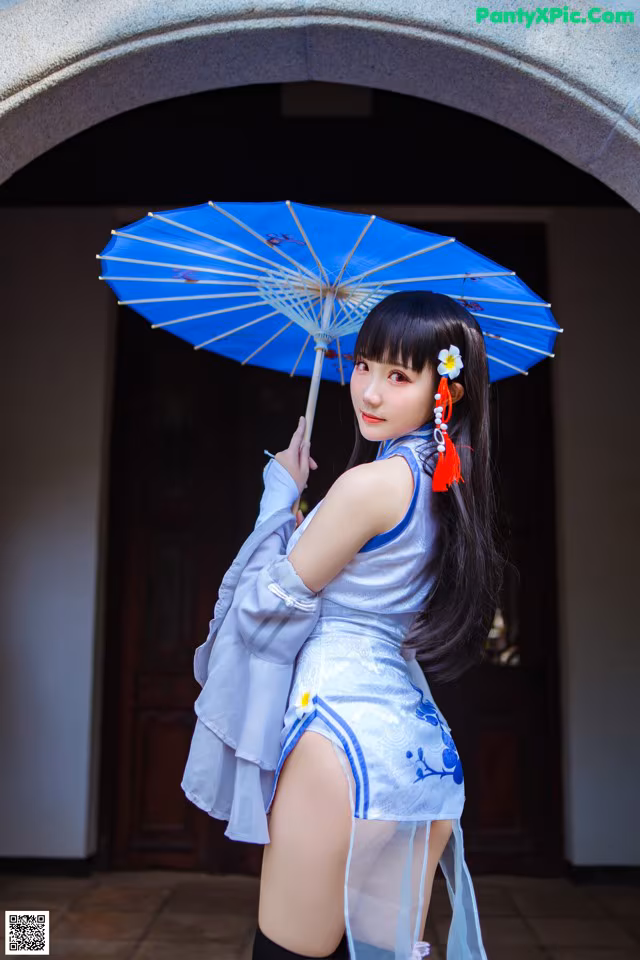 A woman in a blue dress holding a blue umbrella.