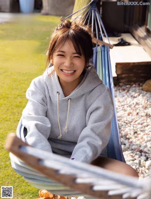 A woman sitting in a hammock smiling at the camera.