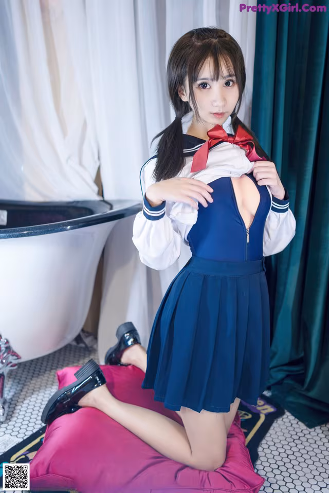 A woman in a school uniform posing on a pink pillow.