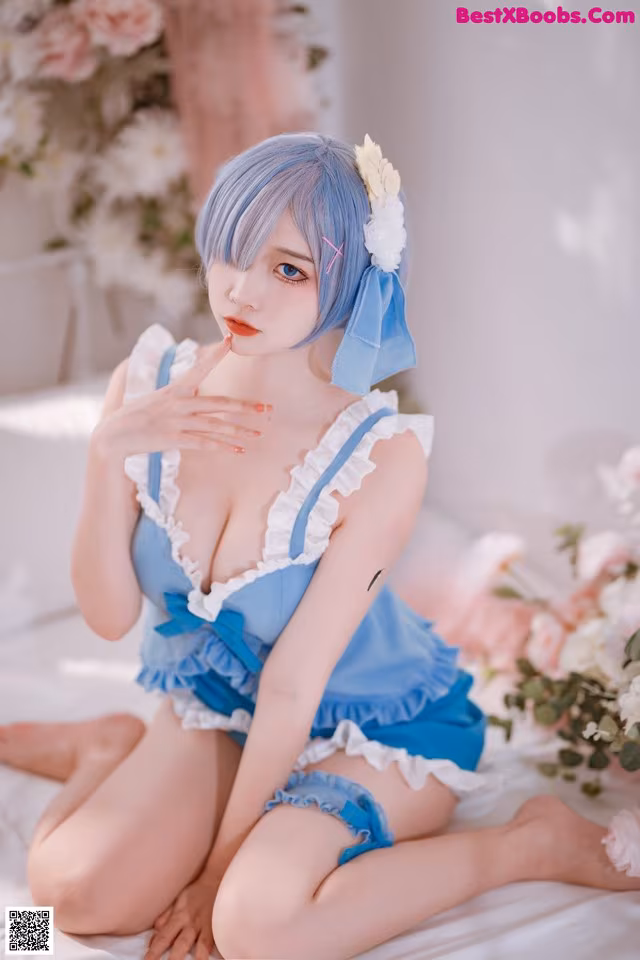 A woman in a blue and white dress sitting on a bed.
