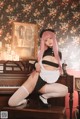 A woman with pink hair sitting on a piano.