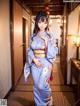 A woman in a blue kimono standing in a hallway.