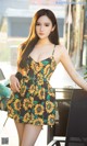 A woman in a sunflower print dress posing for a picture.