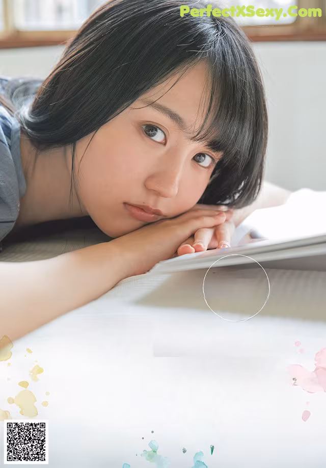 A young woman laying on top of a bed next to a book.