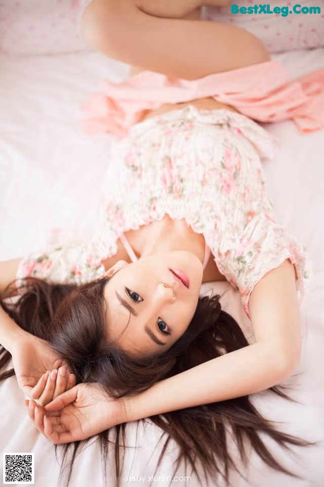 A woman laying on a bed with her hands on her stomach.