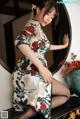 A woman in a chinese dress sitting on a dresser.
