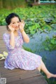 A woman sitting on a wooden dock next to a pond.