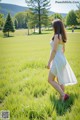 A woman in a white dress is walking through a field.