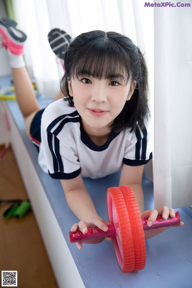 A young girl laying on a bench holding a pink dumbbell.