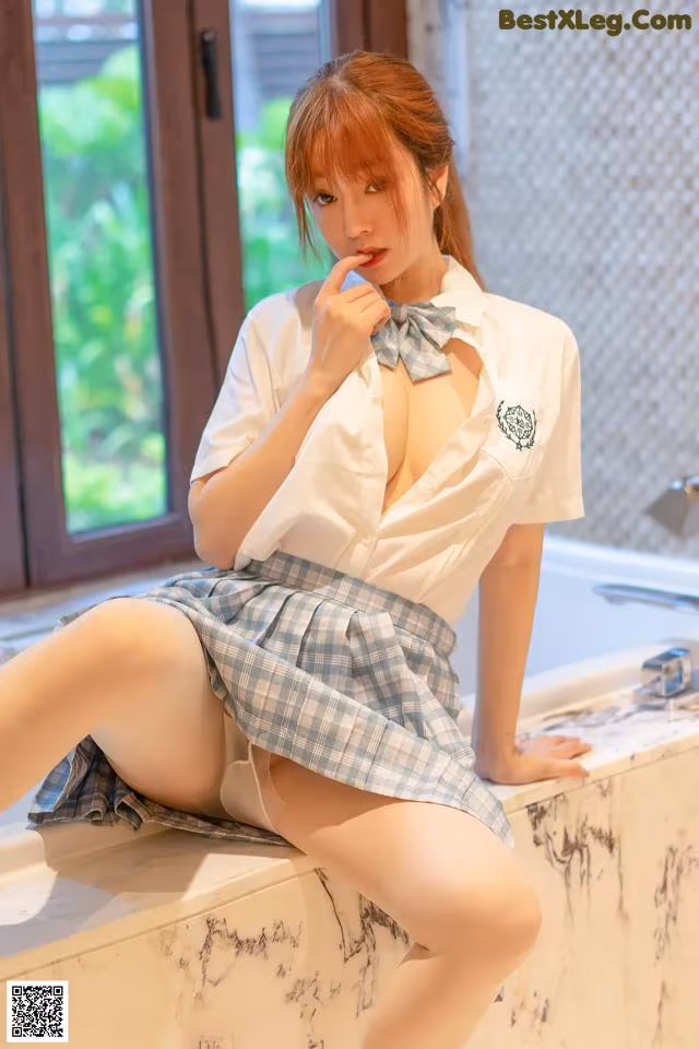 A woman in a school uniform sitting on a bathtub.