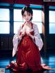 A woman in a red and white kimono sitting on the floor.